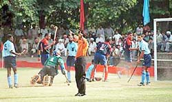 G.C. Parsad of Signals (extreme left) looks at the umpire as the Punjab Police goalkeeper loses his balance in the quarterfinals of the 31st S.N. Vohra's All India Gurmit Memorial Hockey Tournament in Chandigarh on Saturday.
