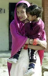 A mother carries her child at a refugee camp