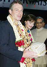Britains Prime Minister Tony Blair is presented with a turban as he and his wife Cherie arrive in Bangalore.