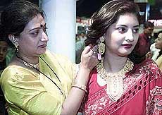 A shopkeeper helps a customer try on gold ornaments during a gold jewellery exhibition in Kolkata on Saturday.