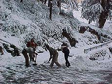 Labourers clear snow from a road