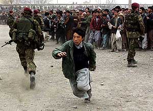 A young Afghan soccer fan runs to get into the stadium.
