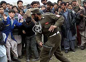 An Afghan security guard beats back soccer fans 