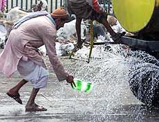 A man tries to collect water leaking from the tank
