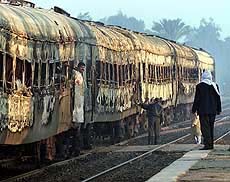 Egyptian rail workers stand beside a train which caught fire
