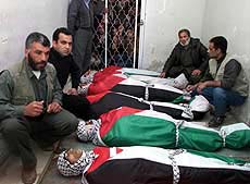 Palestinians sit beside the bodies of nine Palestinians killed by Israeli troops in the West Bank city