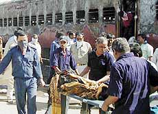 Men carry a charred body