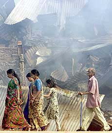 Residents walk past burnt and destroyed buildings in Ahmedabad on Friday.