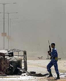 An armed riot policeman walks on a deserted and smoke-shrouded street in Ahmedabad on Friday. 