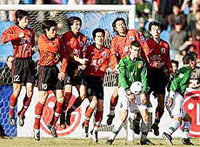 Liaoning defenders (red jerseys) jump to block a free kick by Beijing during their match in the first round of the Chinese first division soccer league in China's capital on Sunday.