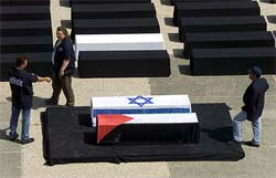 Security guards at the site where peace activists attend coffins covered by Israeli and Palestinian flags 