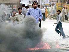 Local residents stand near a burning tyre