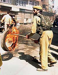 A policeman removes a burning tyre