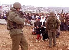 Israeli soldiers stop Palestinians trying to leave the West Bank city of Ramallah
