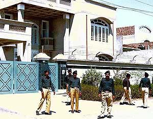 Pakistani policemen stand guard on Friday outside a house in Faisalabad