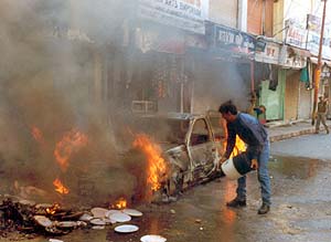 A man tries to extinguish a fire caused by a grenade explosion
