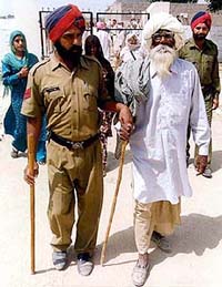 A policeman helps an old man cast his vote at village Tamkot village in the Malout assembly segment on Thursday.