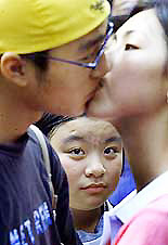 An unidentified girl stares at a couple taking part in a kissing contest