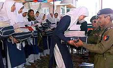 A Border Security Force officer hands over educational material to a school girl 