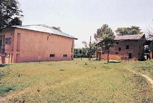 Norahs mud house beside a newly constructed building.