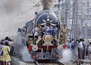 A train pulled by two vintage steam engines makes its way through a cheering crowd