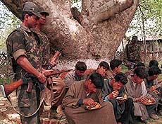 Border Security Force soldiers stand guard as Kashmiri youths take snacks