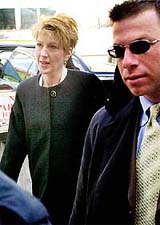 Hewlett-Packard Chairman and CEO Carelton (Carly) Fiorina (L) is escorted by a police officer 