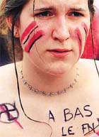 An unidentified woman has a crossed-out swastika and "Down with the National Front" written on her skin