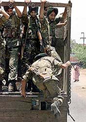 A soldier boards a truck patrolling a riot-hit locality