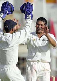 Sachin Tendulkar of India, right, celebrates with wicket keeper Ajay Ratra, left, after taking the wicket of West Indies batsman 
