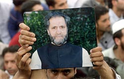 A man holds-up a portrait of Abdul Ghani Lone