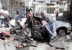 Palestinians look at a car damaged by Israeli tanks