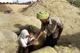 A villager helps his mother and his child out of a newly-prepared bunker