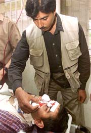 Journalist Sheikh Irfan wipes away blood from the face of his colleague