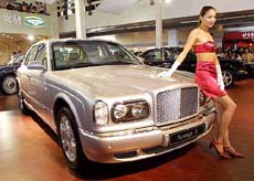 A Chinese model poses next to a Bentley Arnage R during an auto show in Beijing 