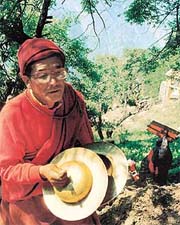 A lama with clanging cymbals proceeding towards a village