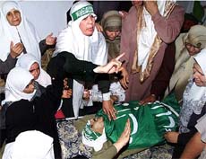 The mother of Palestinian gunman Mahmoudal-Abed asks women not to cry as her son's body is brought home