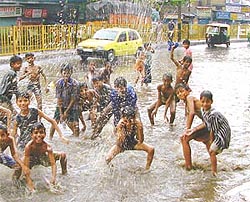 Children prancing in the rain on the main road near Filmistan in Karol Bagh