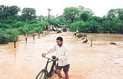 Villagers of Dhanas have a tough time crossing a choe after a heavy rain on Saturday morning 