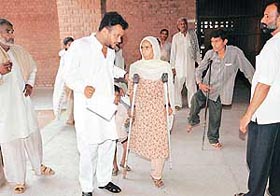 A councillor, Mr Vijay Rana, helps a handicapped woman at a medical checkup camp 