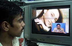 Pakistani shopkeeper Sajjad Ahmed watches a televised speech by General Musharraf