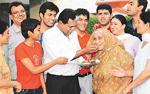 Cricketer Kapil Devs eldest brother Ramesh Nikhanj offers sweets to his mother, Mrs Raj Nikhanj