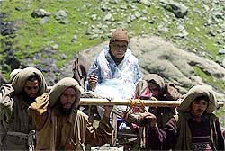 Labourers carry a pilgrim on wooden palanquin