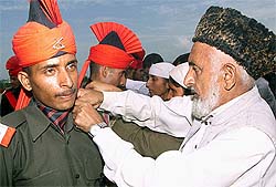 A Kashmiri man adjusts the uniform of his son during the graduation parade at a garrison in Rangreth, Srinagar, on Saturday.