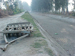 A disc harrow stands next to a dry canal