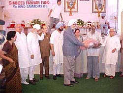 A member of a terrorist-hit family receives aid from a former DGP of Punjab, Mr K.P.S. Gill, as the Punjab Chief Minister, Capt Amarinder Singh, looks on