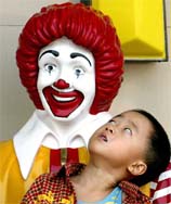A Chinese boy stares up at a statue of Ronald McDonald