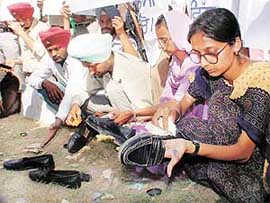 DIET students polish shoes of visitors at the Chhapar Mela to express resentment against not getting promised jobs from the Punjab Government