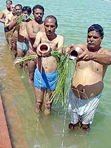 Hindu men offer water to the sun
