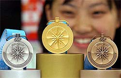 An Asian Games official poses with the gold, silver and bronze medals